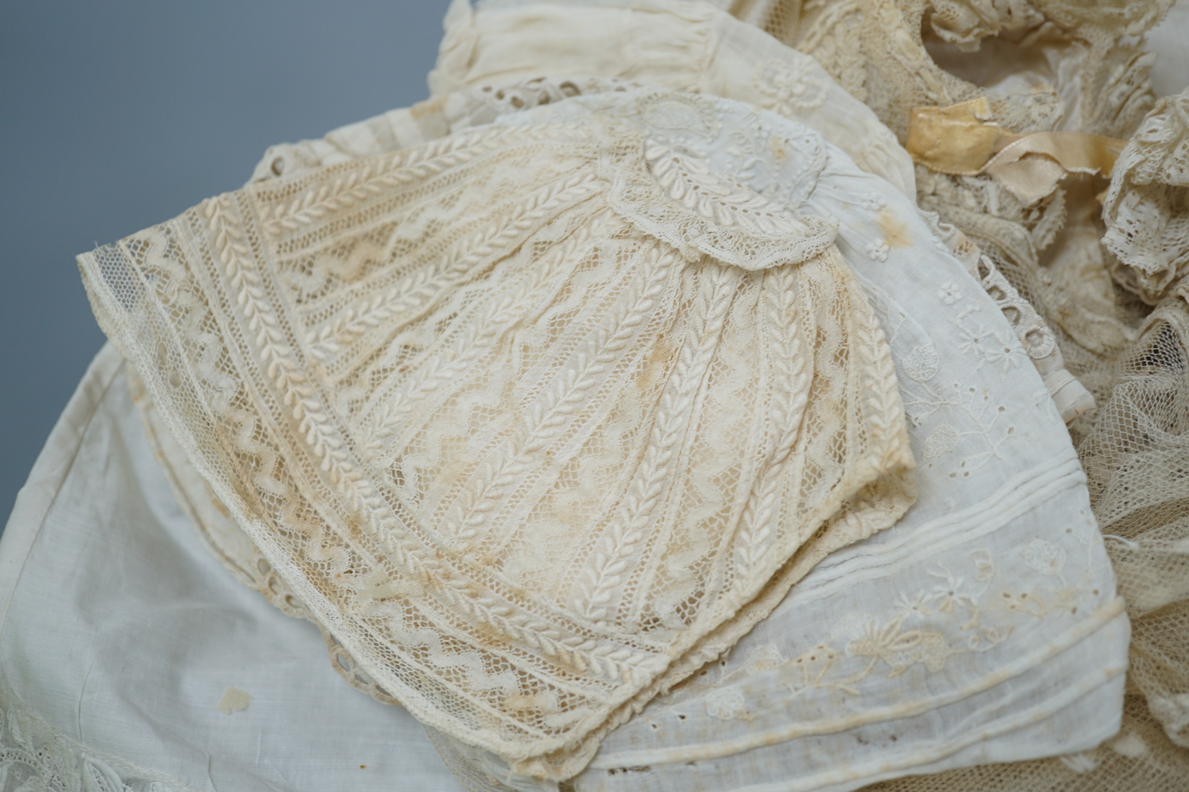 A collection of 19th century babywear, lace and cutwork bonnets and a christening bonnet and veil